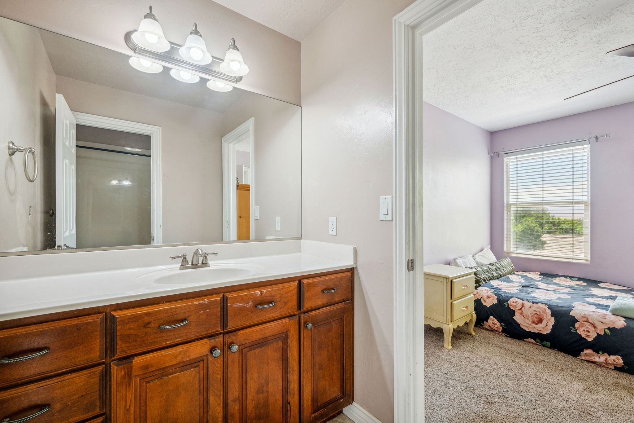 Ensuite bathroom featuring vanity, light carpet, and a textured ceiling
