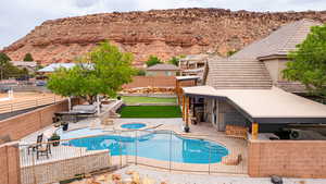 View of pool with a patio area, a fenced backyard, a mountain view, and a pool with connected hot tub