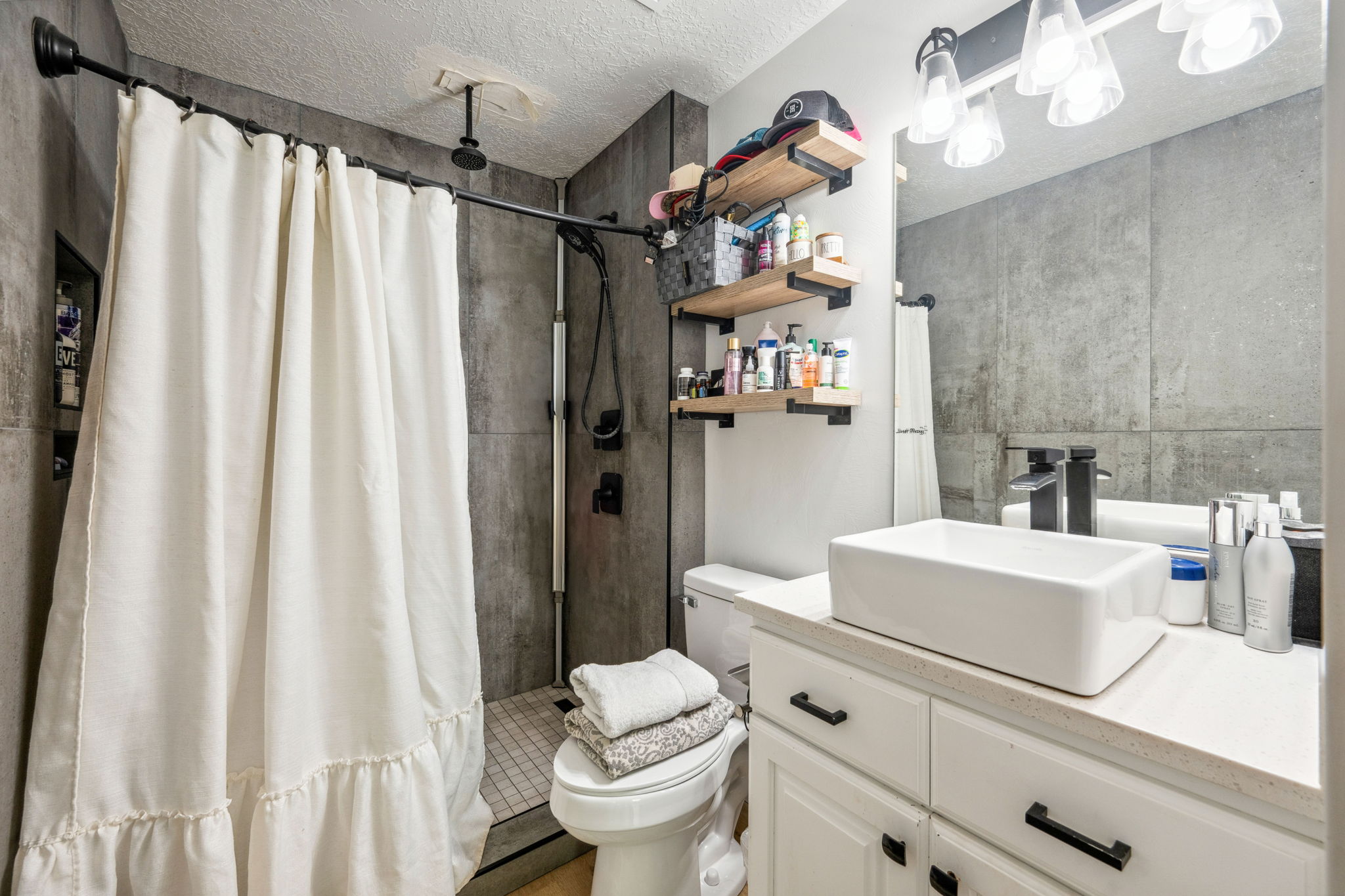 Full bath featuring a tile shower, vanity, and a textured ceiling
