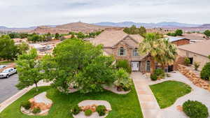 View of front of house with stone siding, a mountain view, a front lawn, and stucco siding