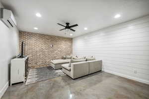Living area with brick wall, a ceiling fan, a wall unit AC, concrete floors, and recessed lighting