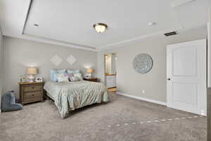 Primary Bedroom featuring carpet flooring, a textured ceiling, a raised ceiling, and ensuite bath