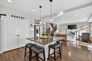 Kitchen with a kitchen bar, pendant lighting, open floor plan, a kitchen island, and stainless steel fridge with ice dispenser