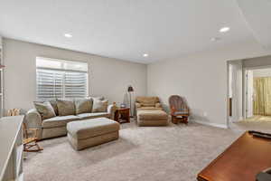 Loft/Living room with light colored carpet, a textured ceiling, and recessed lighting