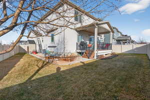 Rear view of house with a fenced backyard, a wooden deck, and a patio area