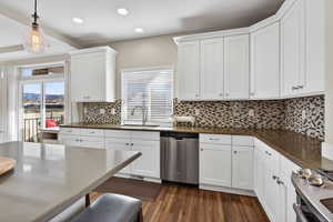 Kitchen with white cabinetry, stainless steel appliances, decorative light fixtures, recessed lighting, and dark wood-style floors