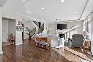 Living room featuring dark wood-style floors, a fireplace, stairway, healthy amount of natural light, and recessed lighting