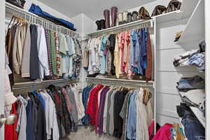 Primary Walk in closet with carpet flooring