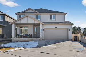 View of front of home with a shingled roof, a porch, stucco siding, a garage, and driveway