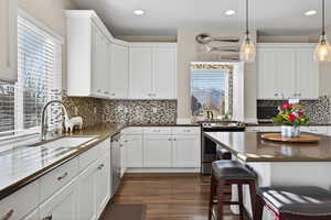 Kitchen with appliances with stainless steel finishes, pendant lighting, white cabinets, and recessed lighting
