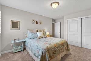Bedroom featuring a closet, carpet flooring, and a textured ceiling
