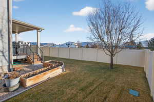 Fenced backyard with a vegetable garden and a patio area