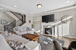 Living area with wood finished floors, a high end fireplace, recessed lighting, stairway, and a raised ceiling