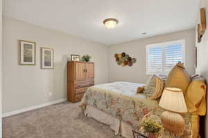 Carpeted bedroom featuring a textured ceiling and baseboards