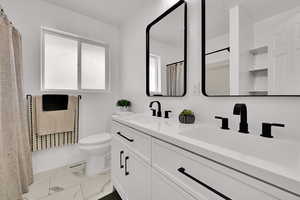 Bathroom with double vanity, curtained shower, and light marble finish flooring