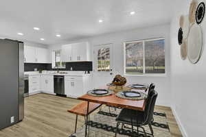 Kitchen with appliances with stainless steel finishes, white cabinetry, light wood-style flooring, recessed lighting, and decorative backsplash