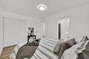 Bedroom featuring a closet, wood finished floors, a textured ceiling, and connected bathroom