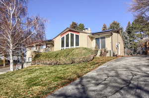 View of front of property with roof mounted solar panels, a chimney, brick siding, and a gate