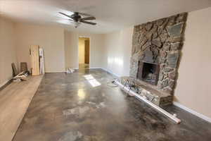 Unfurnished living room with a fireplace, a ceiling fan, concrete floors, and a textured ceiling