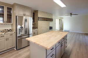 Kitchen featuring stainless steel fridge, light wood-style floors, a kitchen island, and a ceiling fan