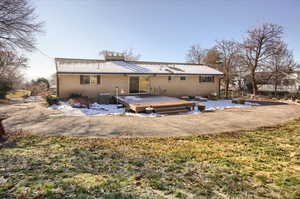 Rear view of house featuring a deck, a chimney, brick siding, and a yard