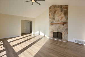Unfurnished living room featuring wood finished floors, a fireplace, ceiling fan, and high vaulted ceiling