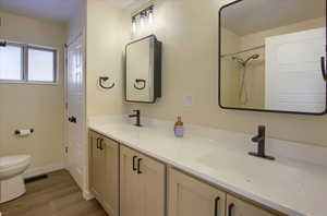 Bathroom featuring double vanity, light wood-style floors, and a shower