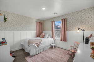 Carpeted bedroom featuring wainscoting and wallpapered walls