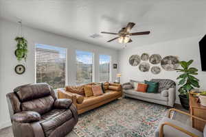 Living area featuring ceiling fan and carpet