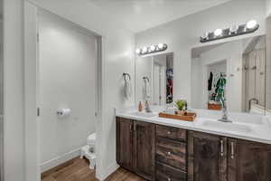 Bathroom with a walk in closet, double vanity, light wood finished floors, and a shower stall