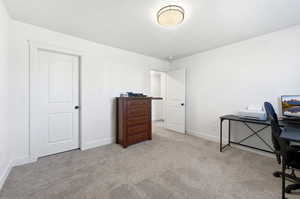 Office area featuring light carpet and baseboards