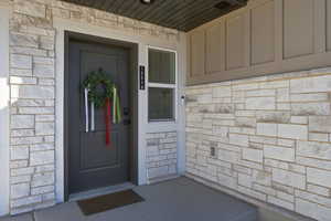 Entrance to property with stone siding and a porch