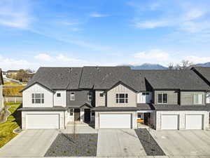 View of front facade featuring board and batten siding, driveway, and roof with shingles