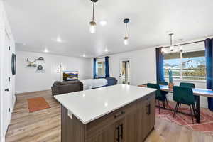 Kitchen with open floor plan, light countertops, a center island, pendant lighting, and LVP flooring