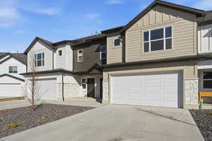 Craftsman inspired home featuring stone siding, board and batten siding, and concrete driveway
