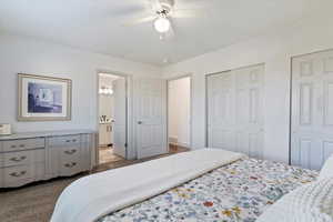 Carpeted bedroom with two closets and ceiling fan