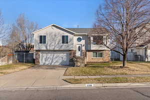 Bi-level home featuring driveway, an attached garage, and brick siding