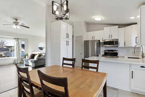 Dining room featuring vaulted ceiling, a ceiling fan, a chandelier, and recessed lighting