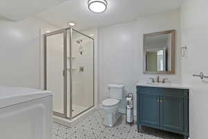 Bathroom featuring washer / clothes dryer, vanity, a culture marble shower stall, and recessed lighting