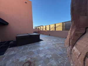 Fenced backyard featuring a hot tub and a large patio area