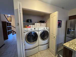Laundry area featuring washer and dryer and light tile patterned floors