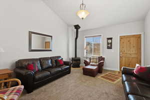 Carpeted living area with a wood stove and lofted ceiling