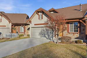 View of front of house featuring concrete driveway, stone siding, a garage, roof with shingles, and a porch