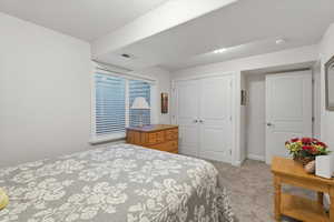 Bedroom with light colored carpet and a closet