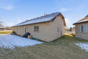 Snow covered rear of property featuring a lawn and a patio