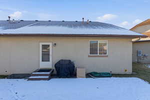 Snow covered property with stucco siding and entry steps