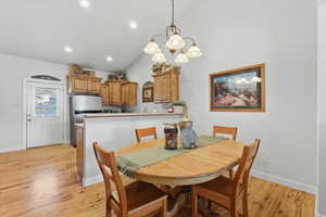 Dining space featuring a chandelier, vaulted ceiling, light wood-type flooring, and recessed lighting