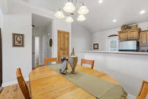 Dining space with light wood-style floors, lofted ceiling, and a chandelier