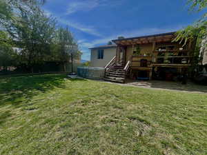 Back of house featuring a yard, a wooden deck, and a patio area