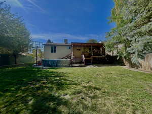 Rear view of house featuring a fenced backyard, stairway, and a wooden deck